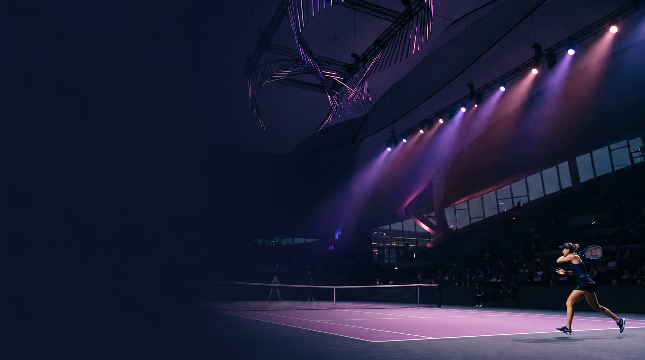 King Saud University Indoor Arena Riyadh at the WTA Finals during an evening session, sleek purple-pink hard court under sculptural lighting rigs, dramatic theatrical purple and rose stage lighting over a deep navy environment with contemporary architecture in shadow